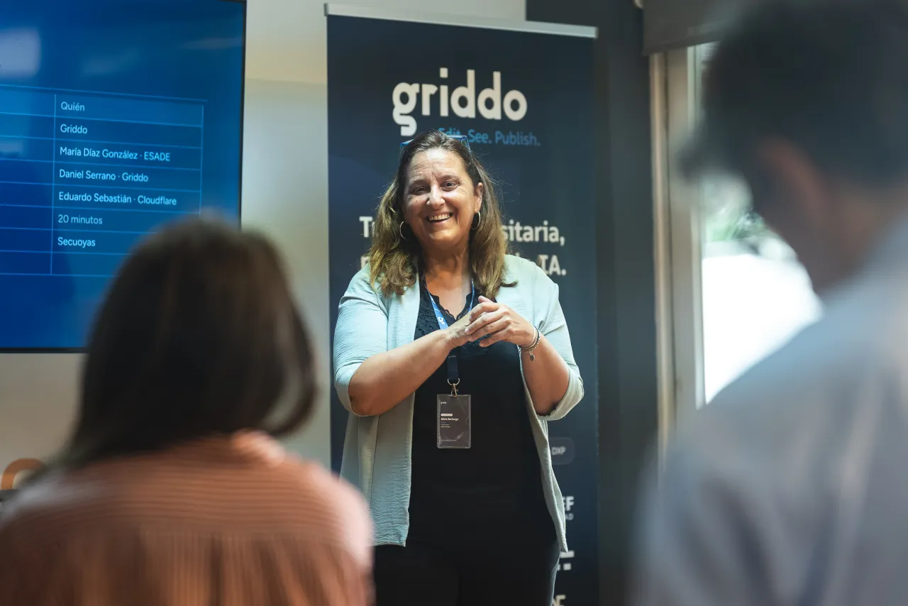 María Díaz presentando, con la agenda del evento proyectada en pantalla